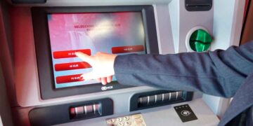 Cliente usando cajero automático seleccionando efectivo; riesgo de bloqueo de cuenta bancaria por incumplir la Ley 10/2010